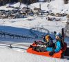 Children riding a winter alpine coaster through a snowy valley