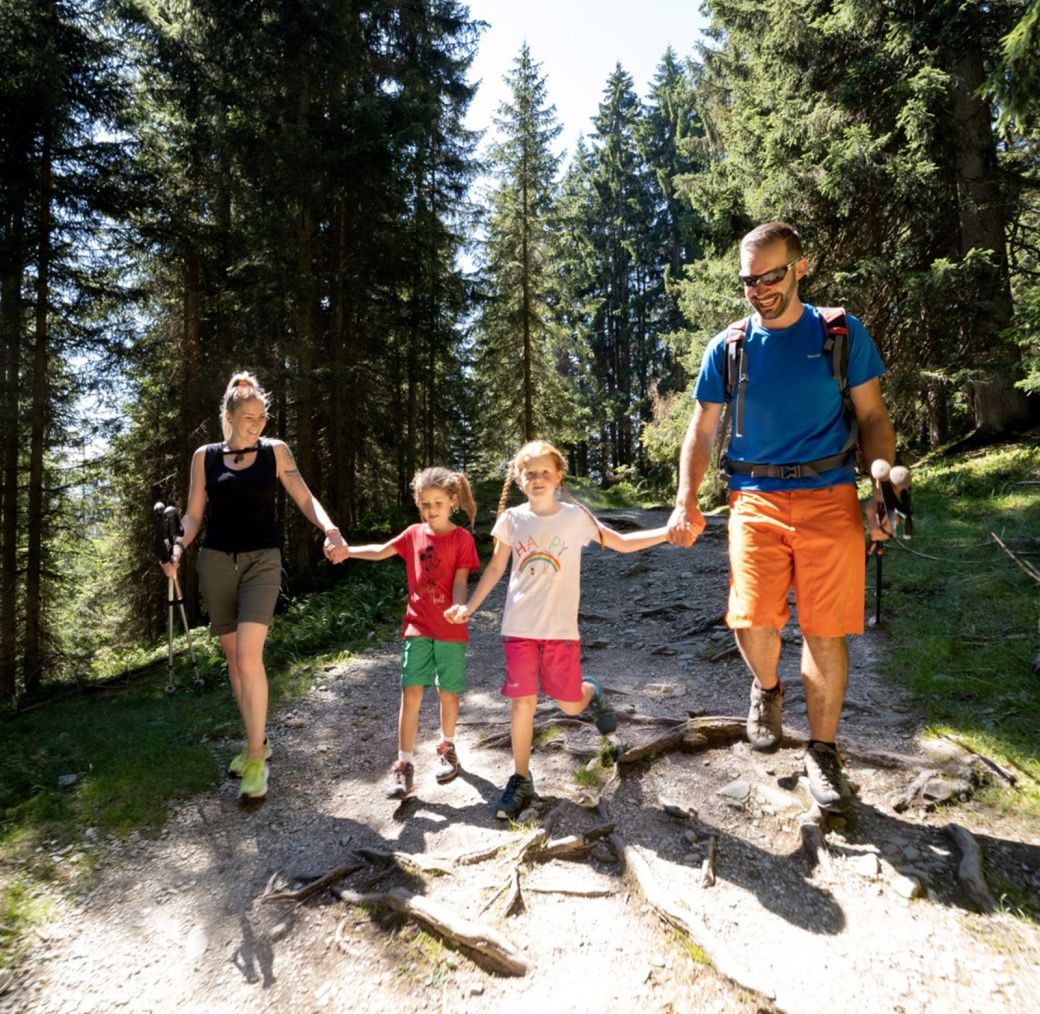 Family with two children hiking together on a forest trail in the mountains