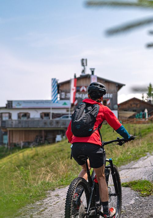 Mountain biker riding uphill on a trail near an alpine hut