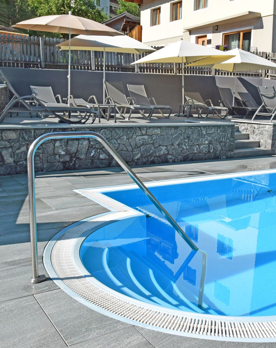 Outdoor pool with entry steps, sun terrace and loungers with umbrellas