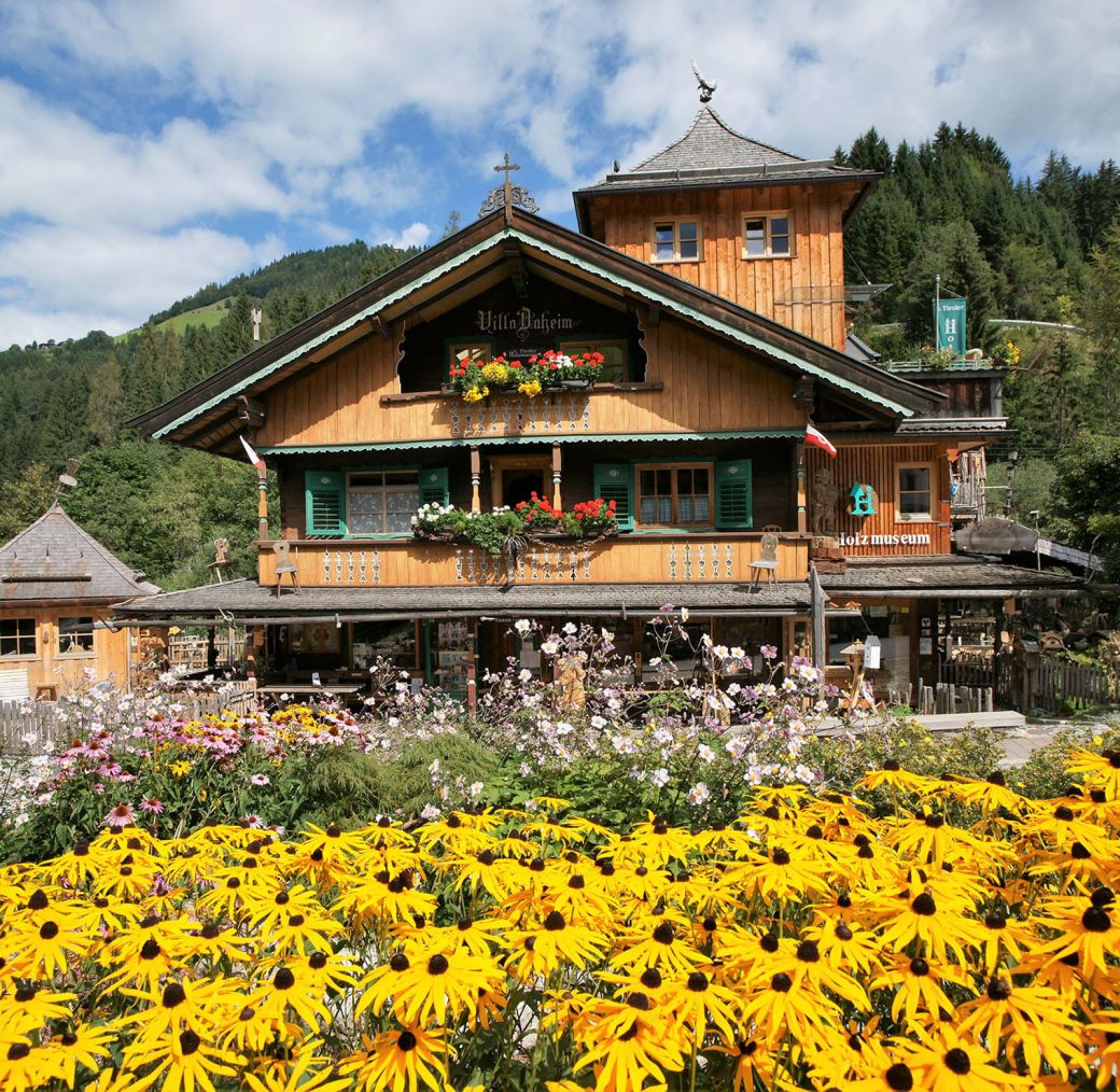 Traditional Tyrolean wooden house with flower-filled balcony and colorful cottage garden