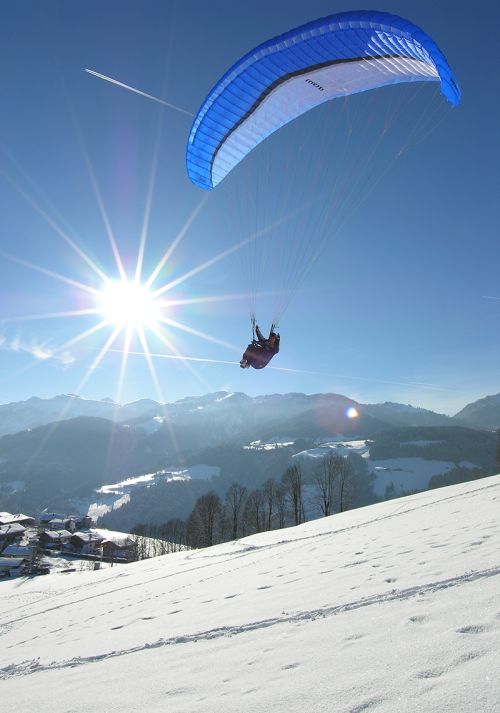 Paraglider flying above a snow-covered alpine mountain landscape