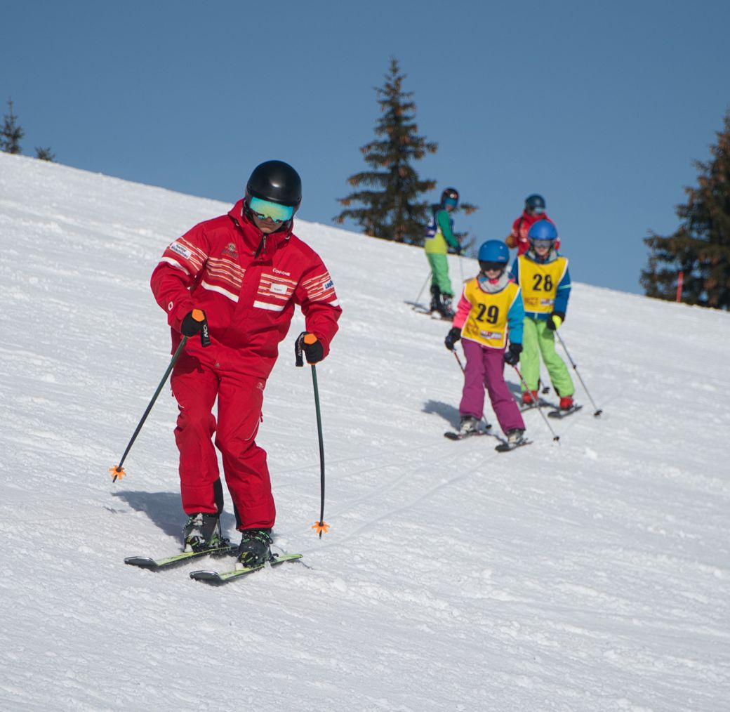 Ski instructor teaching children on a sunny ski slope in winter