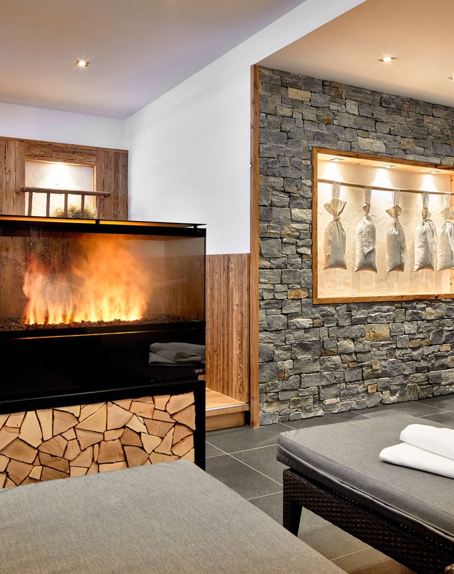 Cozy wellness area with fireplace, natural stone wall and comfortable relaxation loungers