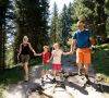 Family with two children hiking together on a forest trail in the mountains