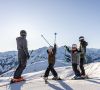 Family with children on skis enjoying views of snow-covered mountain peaks