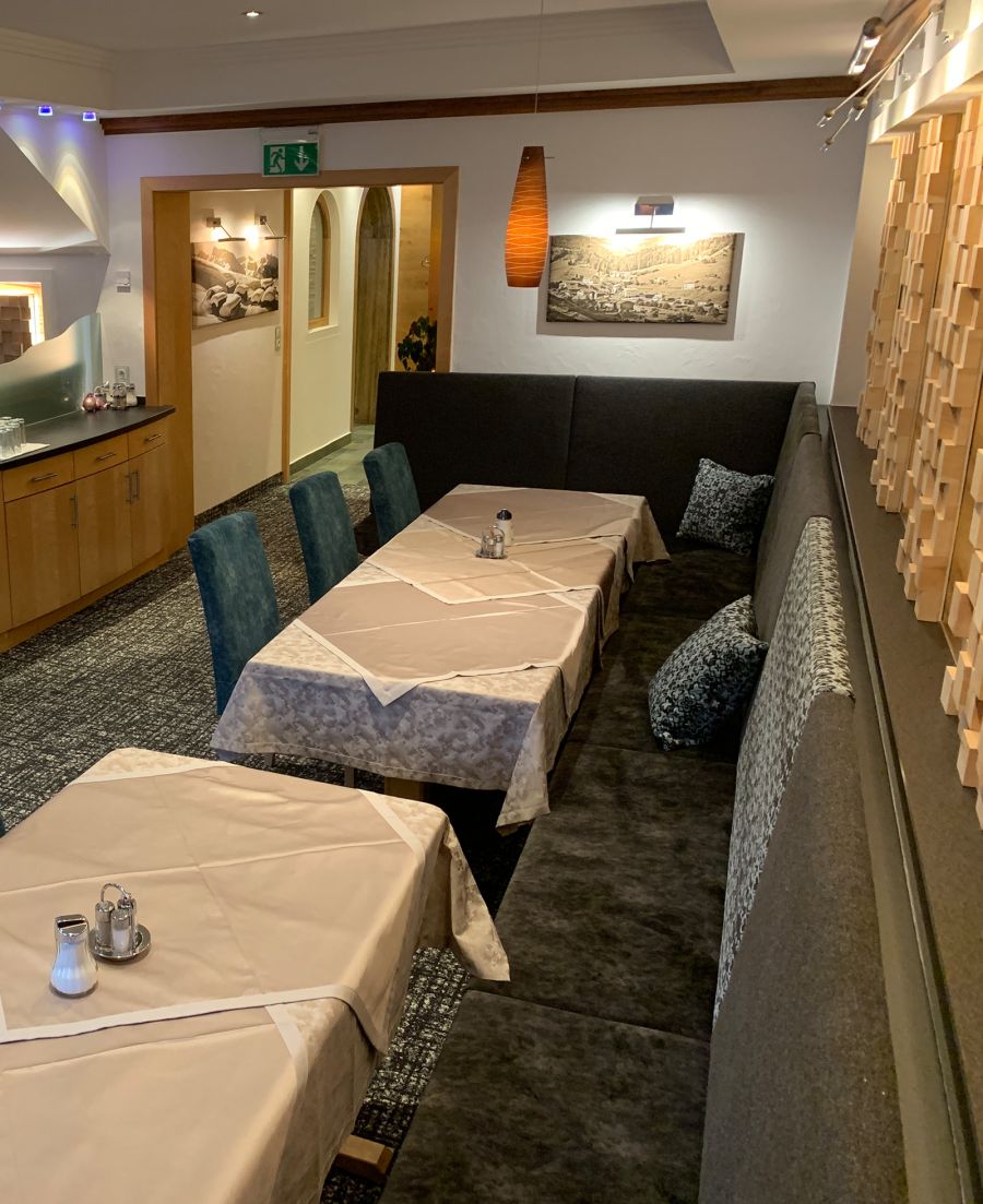 Restaurant area with set tables, upholstered bench seating and chairs