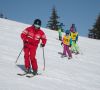Ski instructor teaching children on a sunny ski slope in winter